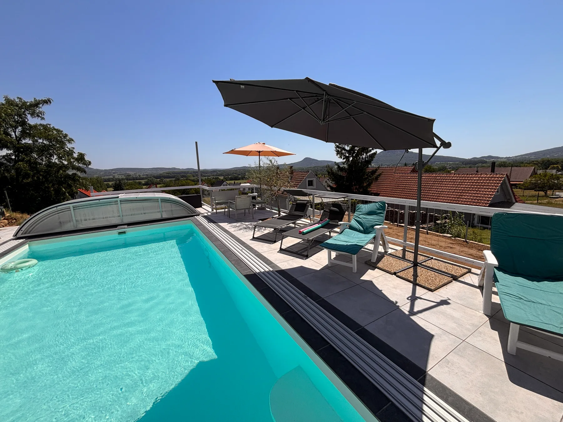 Panorama Pool medence és terasz napernyőkkel a domboldali kilátás felé.