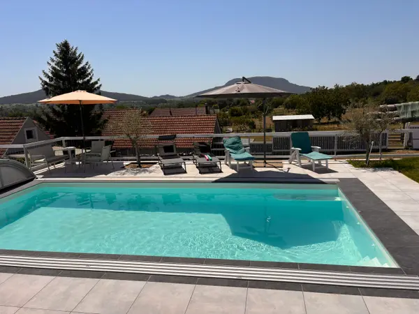 Panorama Pool tágabb nézete a medencével, terasszal és a hegyekkel a háttérben.