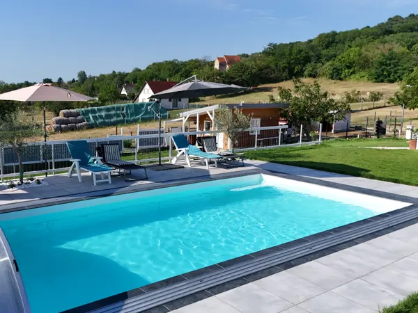 Panorama Pool medence napozóágyakkal és napernyőkkel a domboldali környezetben.