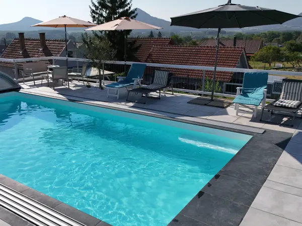 Panorama Pool közelebbi nézete napernyőkkel, pihenőszékekkel és hegyháttérrel.