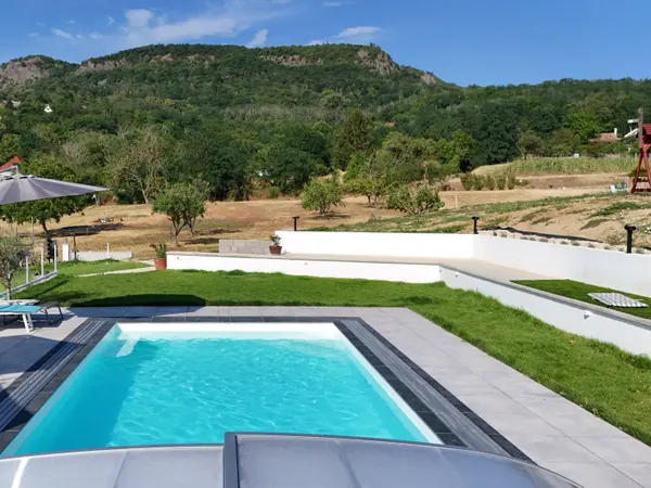 Panorama Pool a medence végéből nézve, gyepes terasszal és hegyoldallal szemben.
